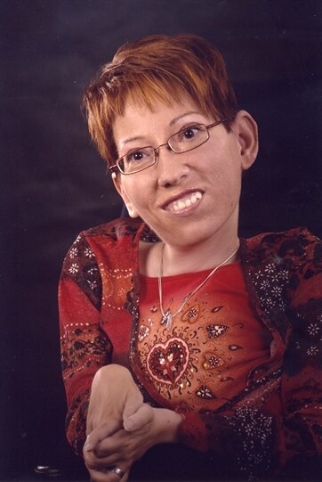 lächelnde Frau im Portraitformat mit Brille und rötlichen kurzen Haaren