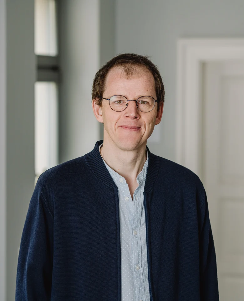 Mann im Portraitformat, Mann im Jacket mit Brille und Blick zum Betrachter