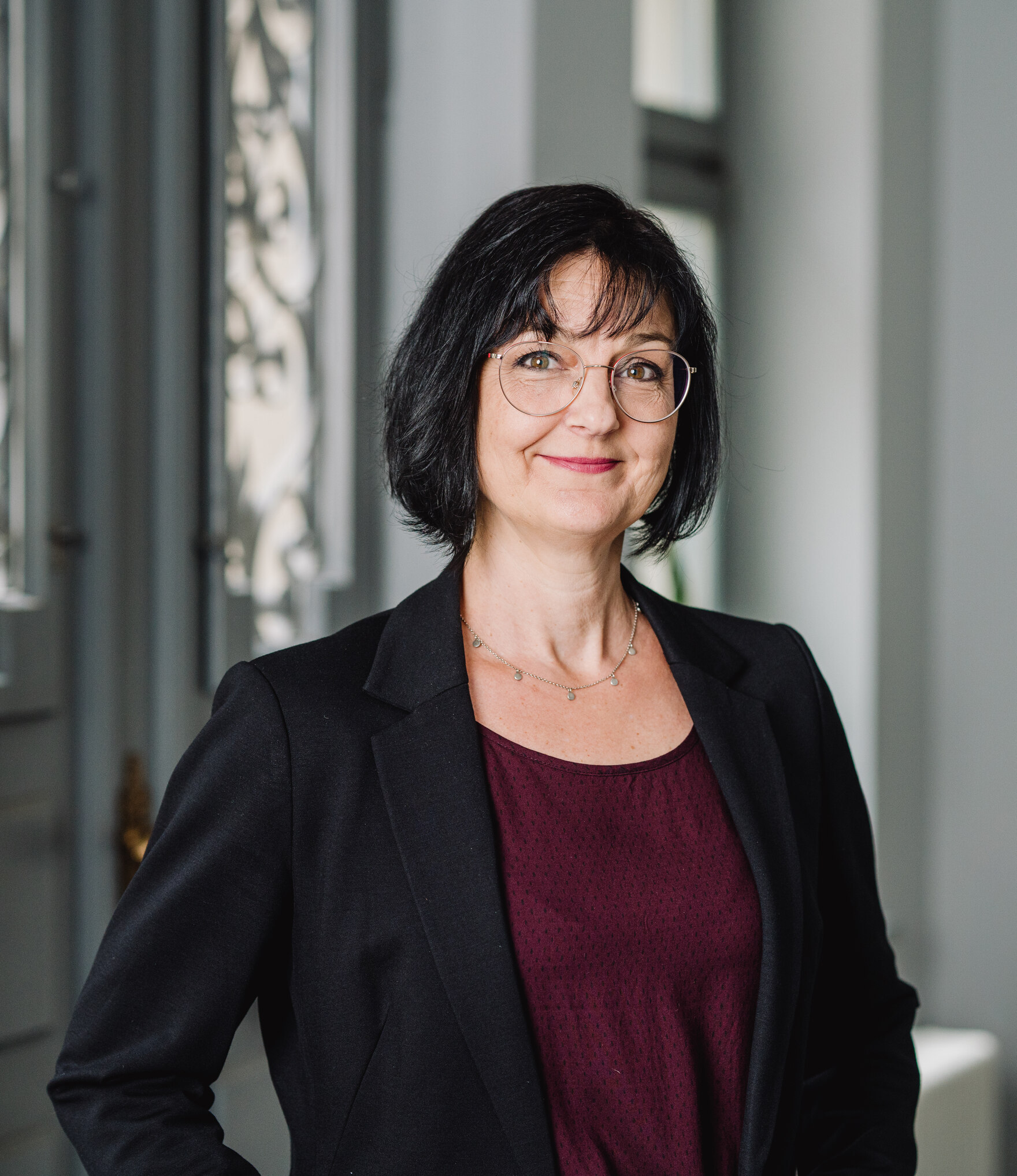 Portaitbild von einer Frau mit Brille und dunklen halblangen Haaren 