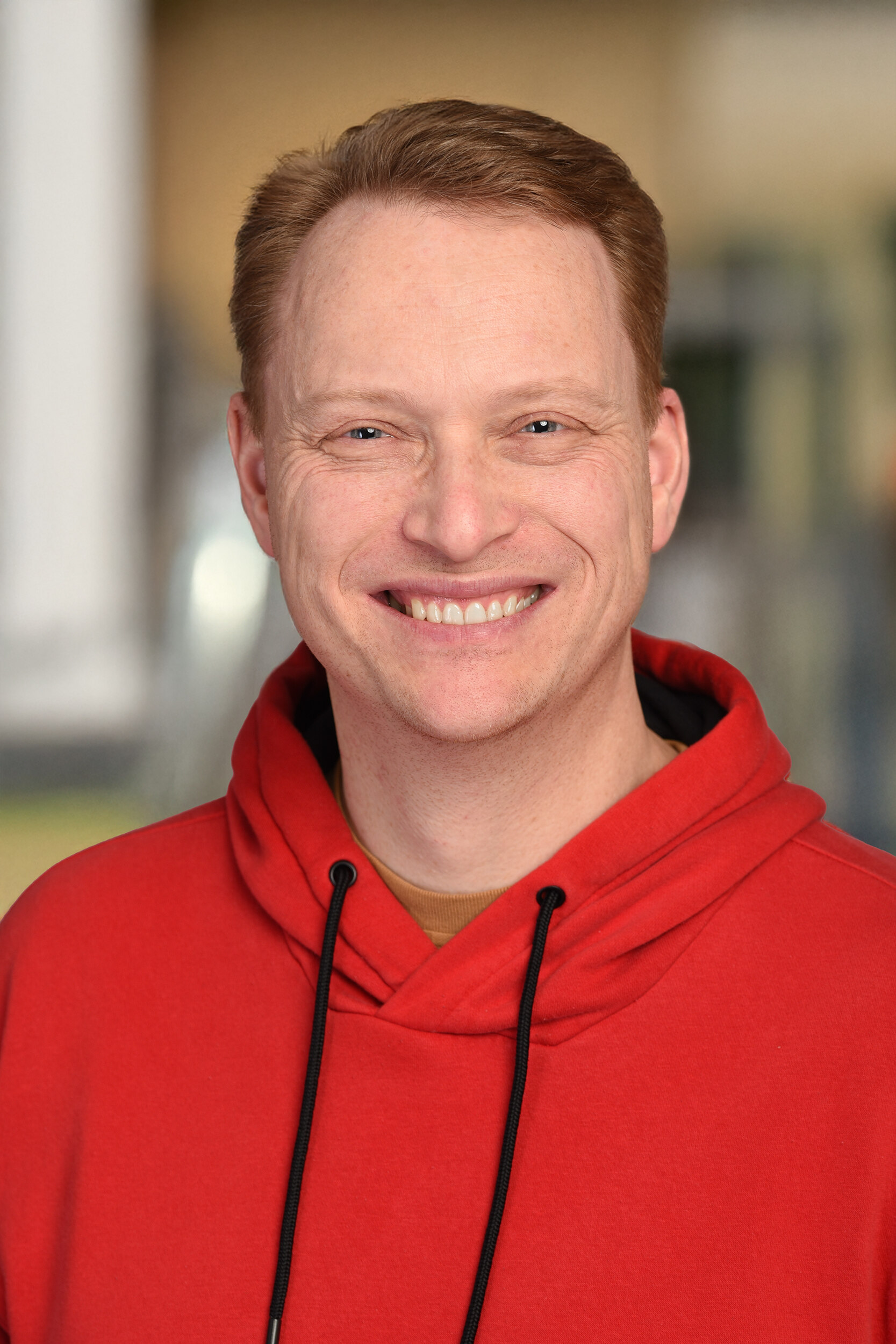 Mann mit kurzen Haaren im Portrait und rotem Pullover