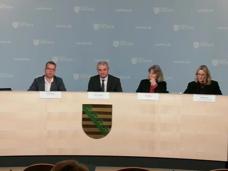 Podium: vier Personen frontal zu sehen, zwei Männer und zwei Frauen