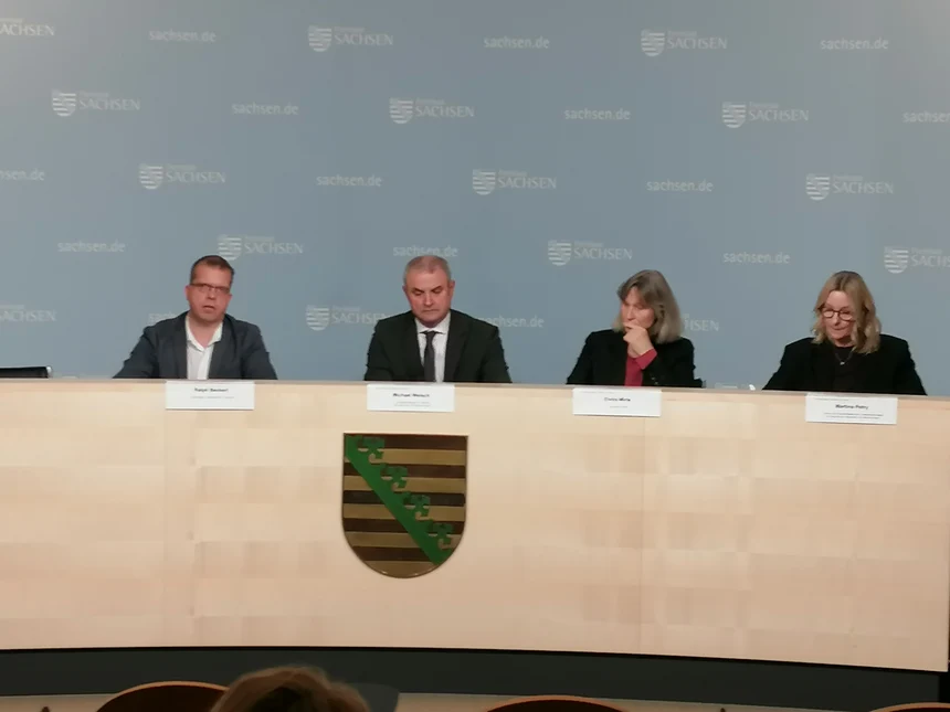 Podium: vier Personen frontal zu sehen, zwei Männer und zwei Frauen